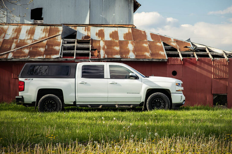 white chevy silverado next to barn with polyfuse tech truck topper